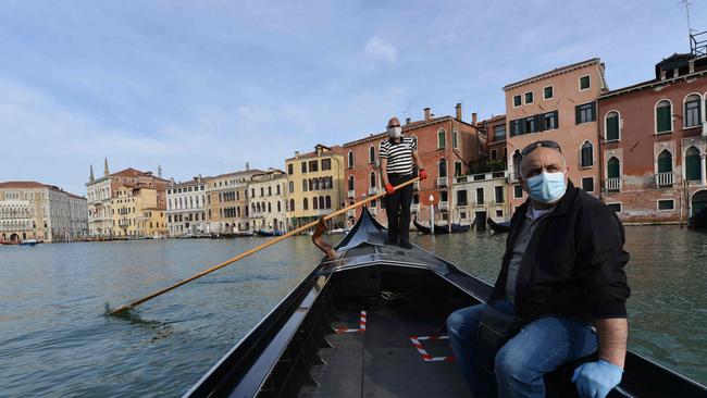 A gondolier wearing a face mask (Rear) transports his very first customer as service resumes at the San Toma embankment on a Venice canal on May 18, 2020 during the country's lockdown aimed at curbing the spread of the COVID-19 infection. Picture: Andrea Pattaro/AFP