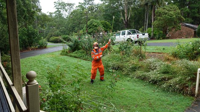 SES volunteer Keith Haycraft tries to secure a rope line to a roof at a house in Symons Avenue, Boambee. Picture: Chris Knight