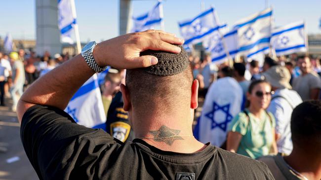 TOPSHOT - A man adjusts his kippah (Jewish skullcap) as right-wing Israelis demonstrate next to the Sde Teman military base near Beersheba, against the detention for questioning of military reservists who were suspected of abuse of a detainee following the October 7 attack in Israel, on July 29, 2024. The military said it has opened an investigation into the "suspected abuse" of a detainee at the Sde Teiman base set up for holding Palestinians arrested in Gaza since the war broke out. (Photo by Menahem Kahana / AFP)