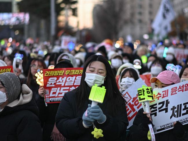 People sing along K-pop music during a protest calling for the ouster of South Korea's President Yoon Suk Yeol outside the National Assembly in Seoul on December 8, 2024. South Korea's main opposition party said on December 8 it will try again to impeach President Yoon Suk Yeol after his declaration of martial law. Yoon averted impeachment on December 7 as huge crowds braved freezing temperatures in another night of protests outside parliament to demand the president's ouster. (Photo by Philip FONG / AFP)