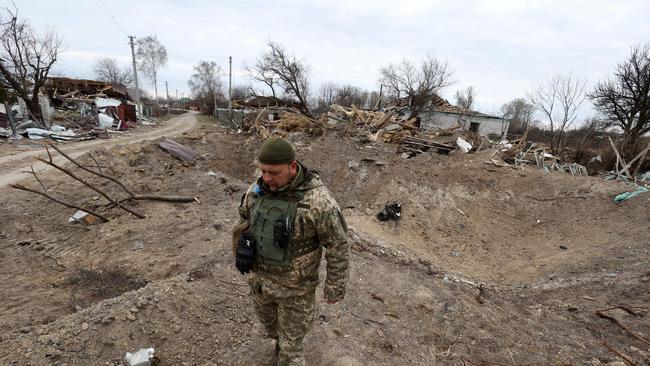 A Ukrainian serviceman walks next to a crater caused by a Russian missile strike in a village on the frontline of the northern part of Kyiv. Picture: Anatolii Stepanov/AFP