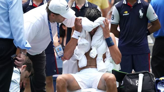 Novak Djokovic gets assistance from medical staff and officials. Photo: AFP