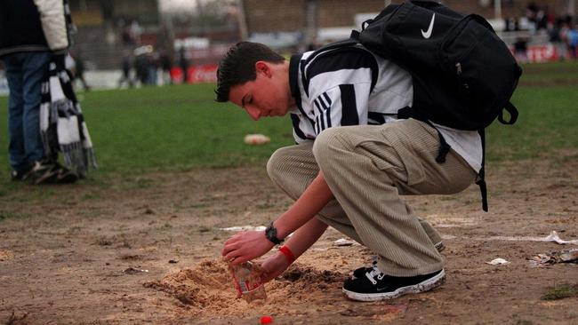 A Magpies fan collects a piece of the centre circle after the game.