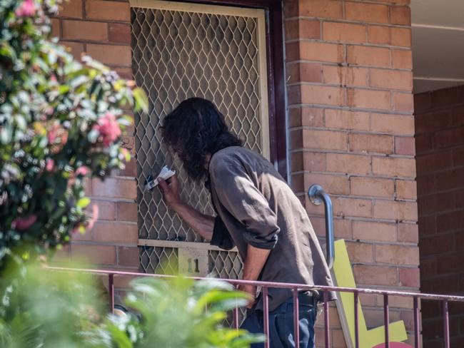 A man grabs what appears to be a white bag from the door’s cut-out hole last month. Picture: Jason Edwards