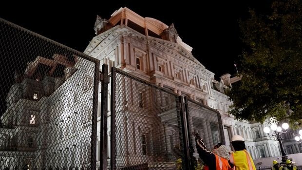 Workers install security fencing outside the Executive Office Building nesar the White House.