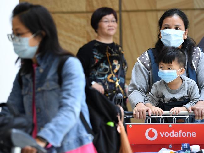 Passengers wearing protective masks arrive at Sydney International Airport in Sydney. Picture: AAP