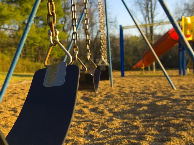 A color image of a child's swing-set at a playground at a local school or park. the photo is a close up of the seat for the swings with a child's slide, monkey bars and playground in the background at a local school or park. there are also trees with green leaves and blue sky in the background. the swings are connected to metal chains that the children swing on during playtime while at school. and the lighting is sunlight during the day.    more playground pictures: click here [url=http://www.istockphoto.com/file_search.php?action=file&lightboxID=4651500][img]http://www.istockphoto.com/file_thumbview_approve.php?size=1&id=5073108[/img][/url]