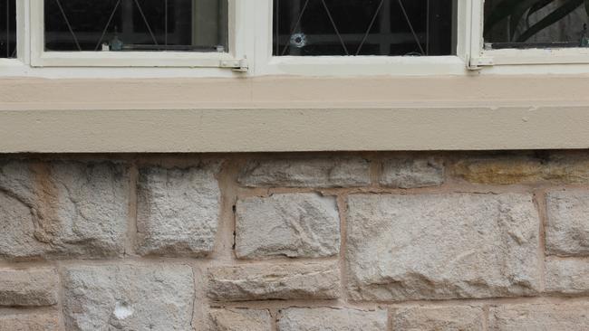 A bullet hole in a window and another mark made by a bullet in the stone work at the home. Picture: Dean Martin