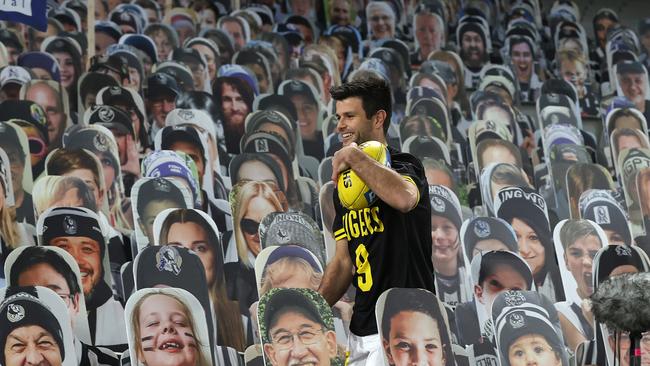 Richmond skipper Trent Cotchin fetches a footy among cardboard cut outs of Collingwood fans. Picture: Michael Klein