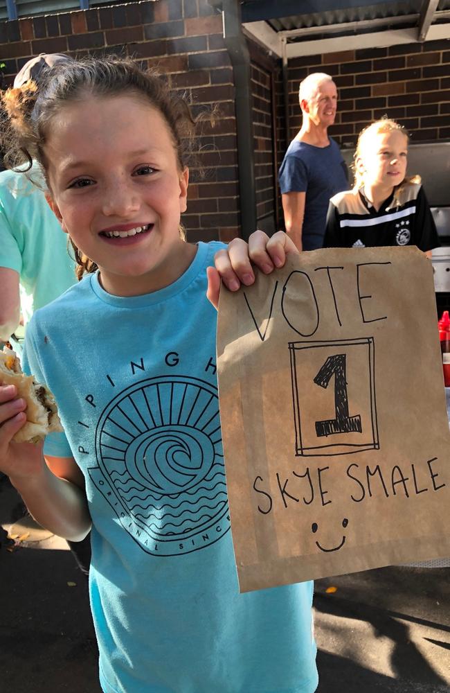 Skye Smale, pupil at Manly Village Public School, helping to man the cake stall and barbecue, with her alternative choice of candidate. Picture: Julie Cross