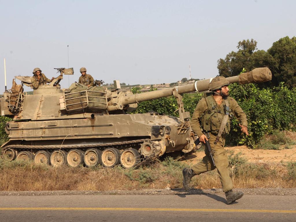 An Israeli soldier runs next to a self-propelled howitzer near the southern city of Ashkelon. Picture” AFP