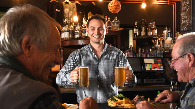News Corp journalist Riley Walter tries his hand at bar work at The Franklin Hotel. He is serving Rob Marner and friend Peter Green, both from Port Vincent. Picture: Tricia Watkinson