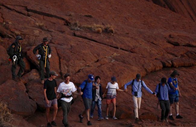 The last climbers finally step off Uluru together.