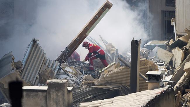 Firefighter scour through the rubble in search of survivors or bodies. Picture: AFP.