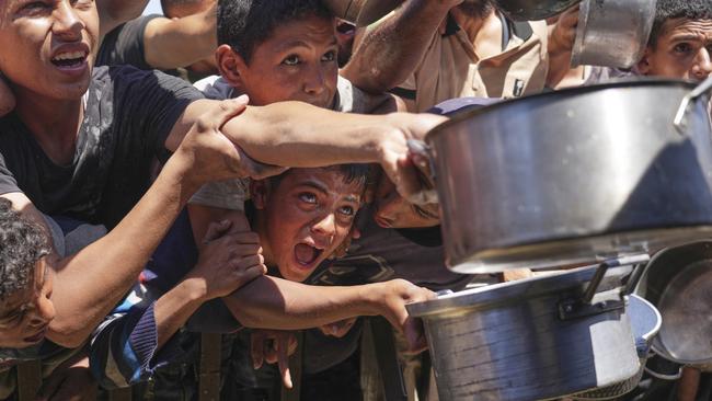 Palestinians struggle to receive cooked food distributed at a community kitchen on Friday in the Muwasi area of Khan Younis, in the Gaza Strip. Picture: Abdel Kareem Hana/AP