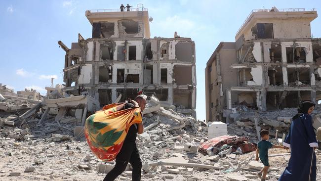 A Palestinian man carries away some items that he was able to salvage amid the rubble. Picture: AFP.