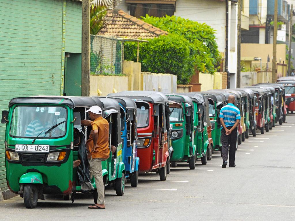 Auto rickshaw drivers queue along a street to buy fuel at a fuel station in Colombo.