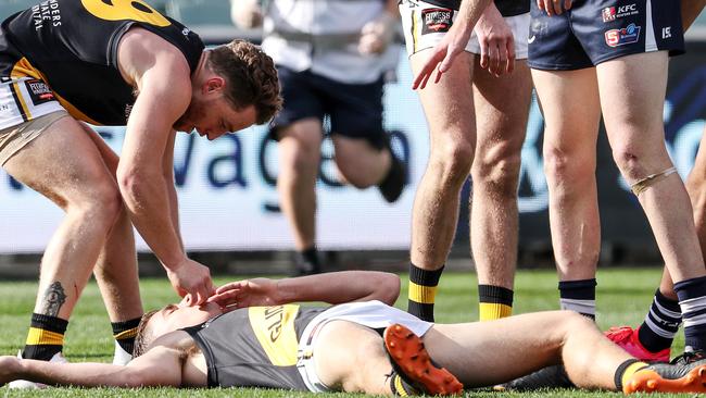 SANFL - Sunday, 5th July 2020 - Glenelg v South Adelaide at the Adelaide Oval. Tigers Carl Nicholson down, concussed. Team mate Tigers Michael Virgin takes out his mouth guard for him. Nicholson taken from the oval. Picture: Sarah Reed