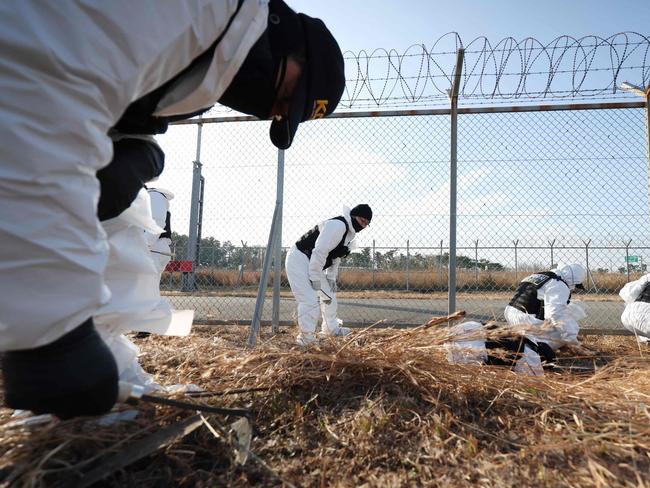 TOPSHOT - Members of a police scientific investigation team conduct a search operation near the site where a Jeju Air Boeing 737-800 aircraft crashed and burst into flames at Muan International Airport in Muan, some 288 kilometres southwest of Seoul on January 1, 2025. The Boeing 737-800 was carrying 181 people from Thailand to South Korea when it crashed on arrival on December 29, killing everyone aboard -- save two flight attendants pulled from the twisted wreckage of the worst aviation disaster on South Korean soil. (Photo by YONHAP / AFP) / - South Korea OUT / NO ARCHIVES -  RESTRICTED TO SUBSCRIPTION USE