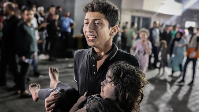 A Palestinian carries a child injured in an Israeli shelling on the Al-Ahli Arab hospital to al-Shifa hospital in Gaza City. Picture: Reuters