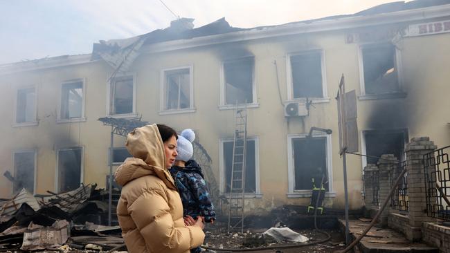 A local resident and her child walks past the railway station destroyed by a Russian missile attack in Ukraine. Picture: AFP