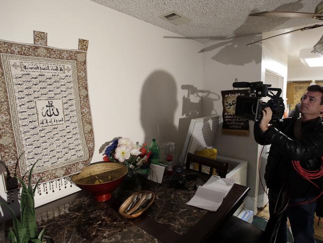 A member of the media films a wall tapestry displaying religious writing in the living room of an apartment in Redlands, California. Picture: AP