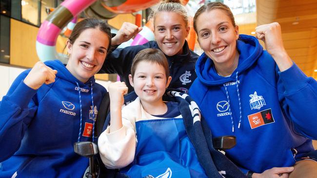 North Melbourne players Bella Eddey (left), Emma King (right) and Carlton star Abbie McKay (top) with 2024 AFLW premiership cup presenter Imogen Mulgrew. Picture: Mark Stewart