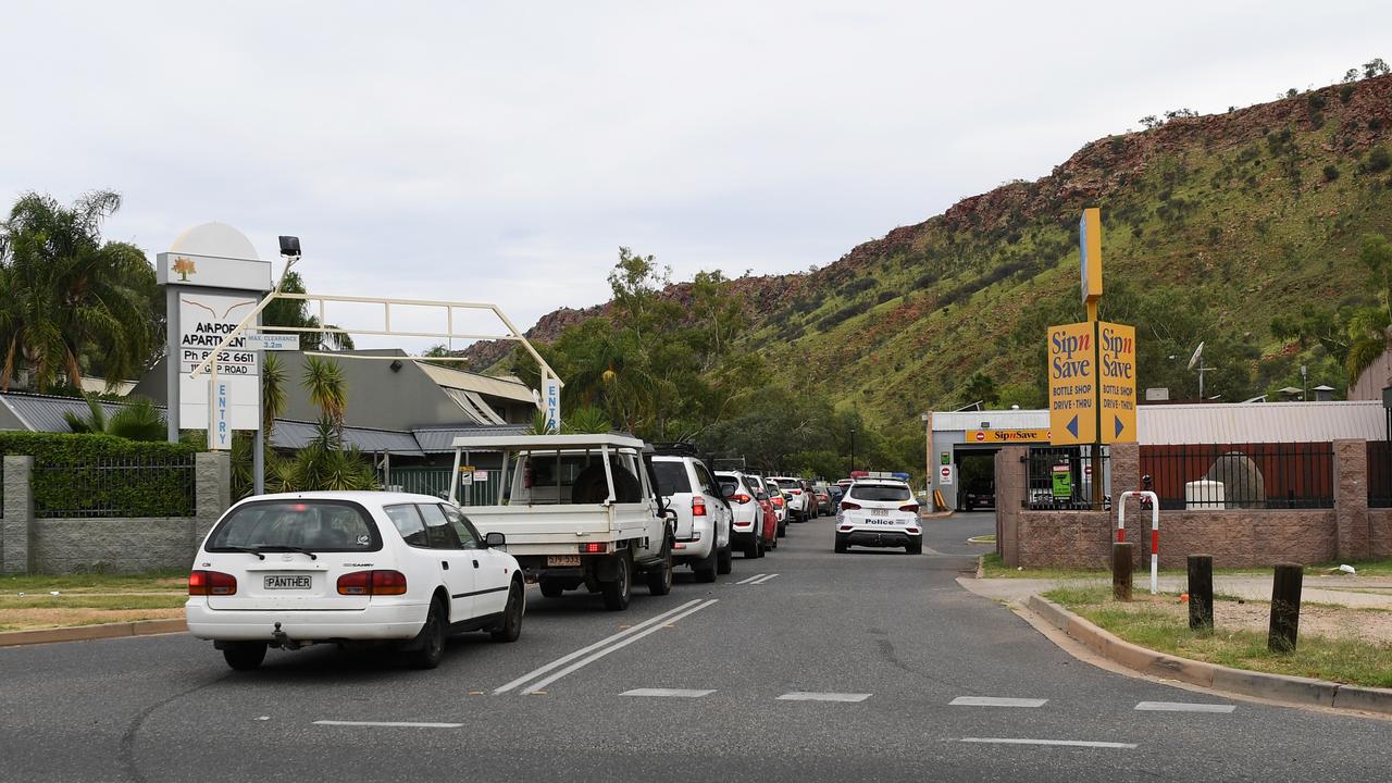 Police presence as cars line-up at the 3pm opening of the Gap View Hotel bottle shop in Alice Springs. Picture Mark Brake