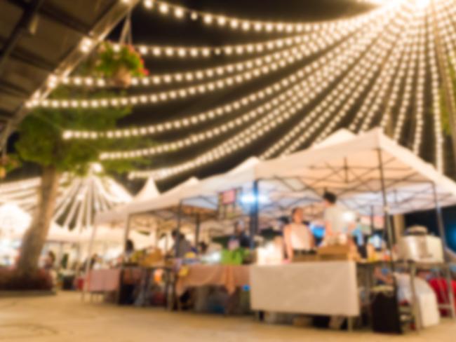 blurred background of flea market at night weekend for sellers meet customers  to buy and sell anything. night markets fairy lights generic Photo: iStock