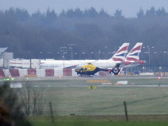 A police helicopter flies over the runway at Gatwick, as the airport remains closed with incoming flights delayed due to rogue drones. Picture: AP