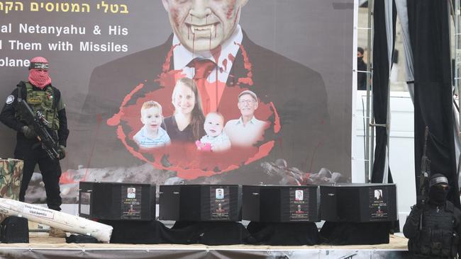 A Hamas militant stands on stage near coffins during the handover of deceased hostages. Picture: REUTERS/Ramadan Abed