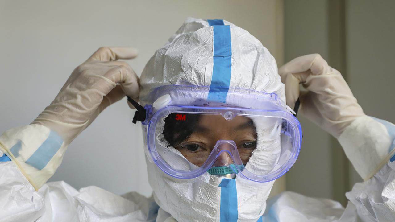 A doctor puts on a protective suit and goggles at a hospital in Wuhan. Picture: Chinatopix via AP