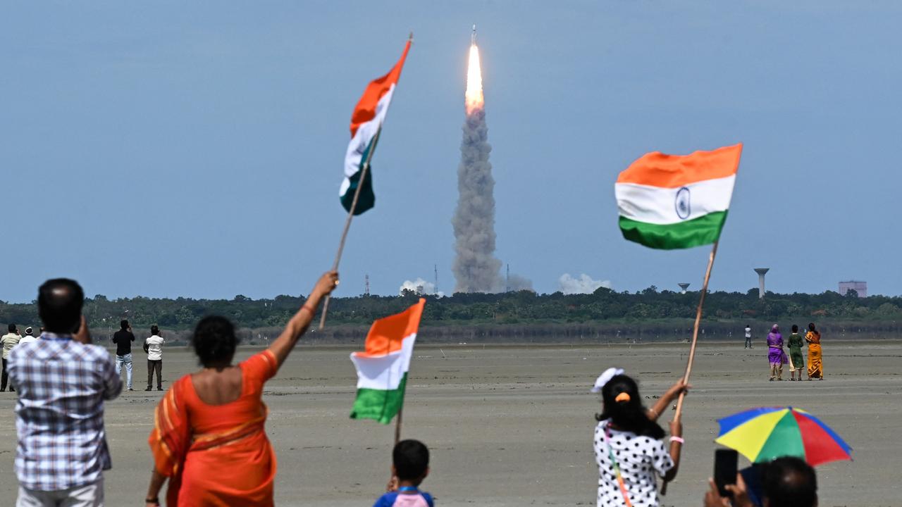 People wave Indian flags as rocket carrying the Chandrayaan-3 spacecraft lifts off from the Satish Dhawan Space Centre in Sriharikota, an island off the coast of southern Andhra Pradesh state on July 14, 2023. (Photo by R.Satish BABU / AFP)