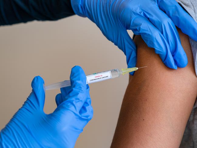 This picture depicts a young female clinician using a syringe to inject a concept COVD-19 liquid vaccine into a young girl patient during the Phase 3 vaccination human trials.