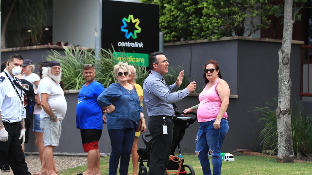 Officials from Centrelink speak to the lines of people waiting at Southport Centrelink. Picture: Adam Head.