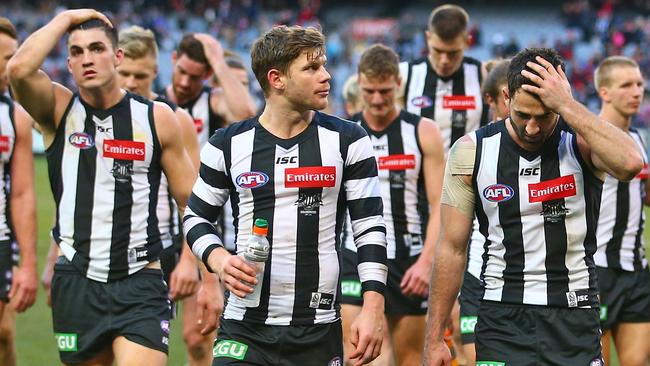 Collingwood players walk off the MCG after the loss to Essendon.