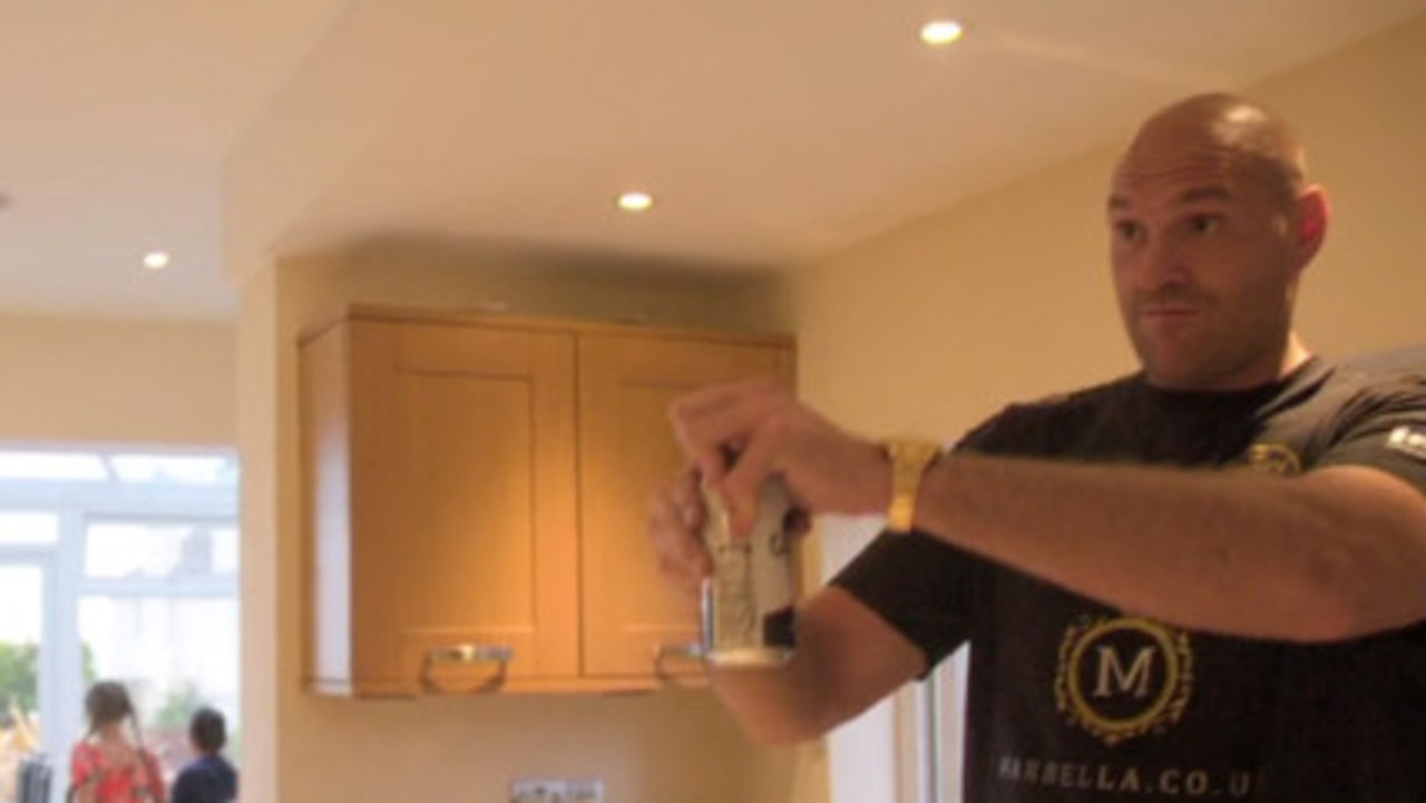 Fury cracking open a drink in his kitchen.