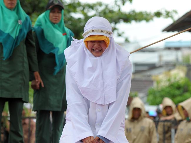 A Muslim girl gets caned 23 strokes after being caught in close proximity with her boyfriend in Banda Aceh on October 17, 2016. Out of seven couples caught spending time together outside marriage, 13 were caned while one girl was spared after it was discovered that she was pregnant. Indonesia's Aceh province has gained international infamy for its strict Islamic laws. / AFP PHOTO / CHAIDEER MAHYUDDIN