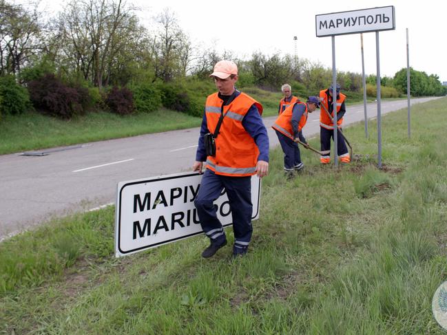 Municipal workers change Ukrainian road signs to Russian outside the city of Mariupol. Picture: AFP