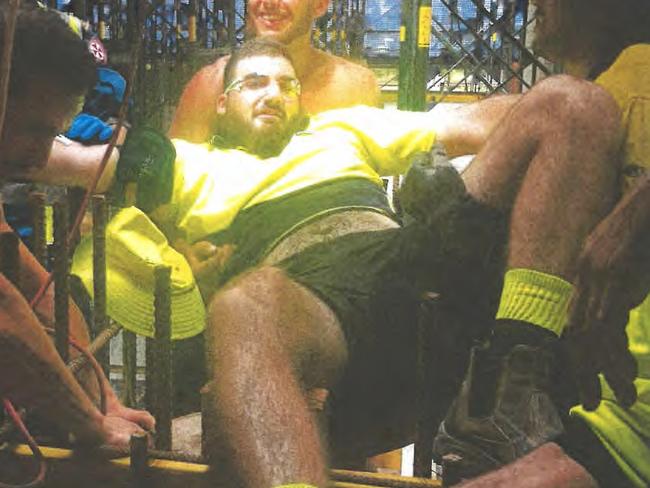 Workmates and fire fighters help teenager Michael Khouri after he plunged through an opening in the floor at one of Toplace's developments.,