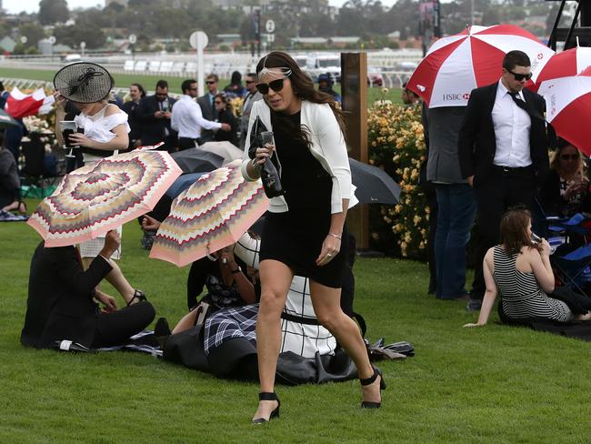 Race goers try to avoid the wind and rain on Victoria Derby Day at Flemington Racecourse on Saturday, November 1, 2014, in Flemington, Australia. Picture: Hamish Blair