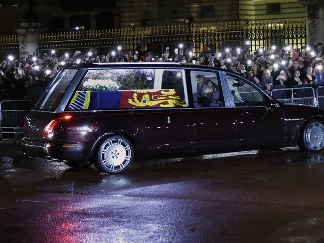 The hearse carrying the flag-draped casket of Queen Elizabeth II enters the centre gate at Buckingham Palace where large crowds have gathered. Picture: Getty