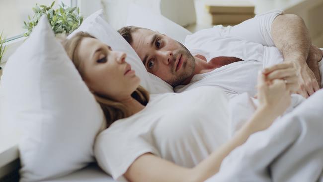 Closeup of couple with relationship problems having emotional conversation while lying in bedroom at home