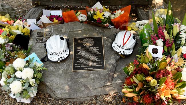 Flowers and the men’s helmets adorn a plaque of remembrance at the Horsley Park Rural Fire Brigade. Picture: AAP