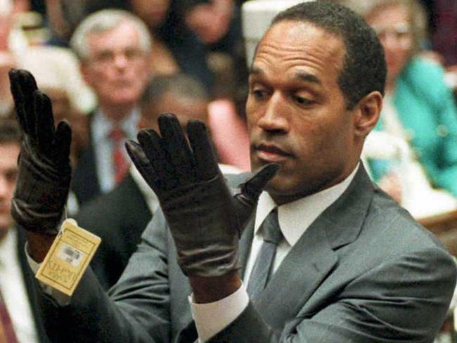 USA actor, sports identity Orenthal (OJ) Simpson (l) trying on leather gloves linked to the murders during his murder trial 21 Jun 1995.