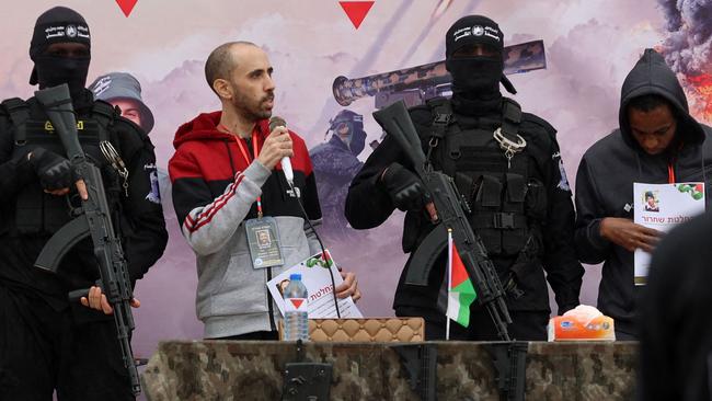 TOPSHOT - Israeli hostages Avera Mengistu (R) and Tal Shoham (3rd-L) are flanked by Palestinian Hamas fighters as they stand on a stage during their release in Rafah in the southern Gaza Strip on February 22, 2025. Masked militants paraded Tal Shoham and Avera Mengistu on stage in the southern Gazan city of Rafah before handing them over to officials from the Red Cross. (Photo by Omar AL-QATTAA / AFP)