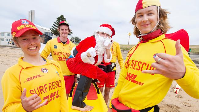 Santa prepares for Christmas Day with Torquay surf life savers Meg Davy, Josh Whitty and Jake Campbell. Picture: Alan Barber