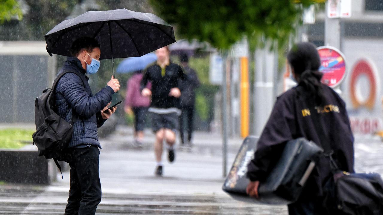 People are seen walking while holding an umbrella on a rainy day in Melbourne. Picture: NCA NewsWire / Luis Enrique Ascui