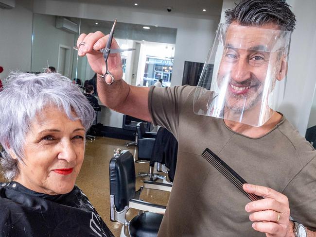 Coca Hair Salon owner Don Donato wears a plastic face shield while cutting Nella Lofts' hair. The new product is called Rapid Shield and is designed and manufactured in Coburg's Space Tank Studio. Picture: Jake Nowakowski