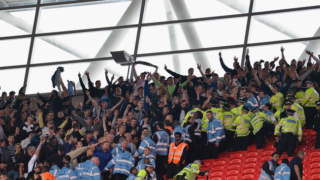 Police and stewards hold back Millwall fans.
